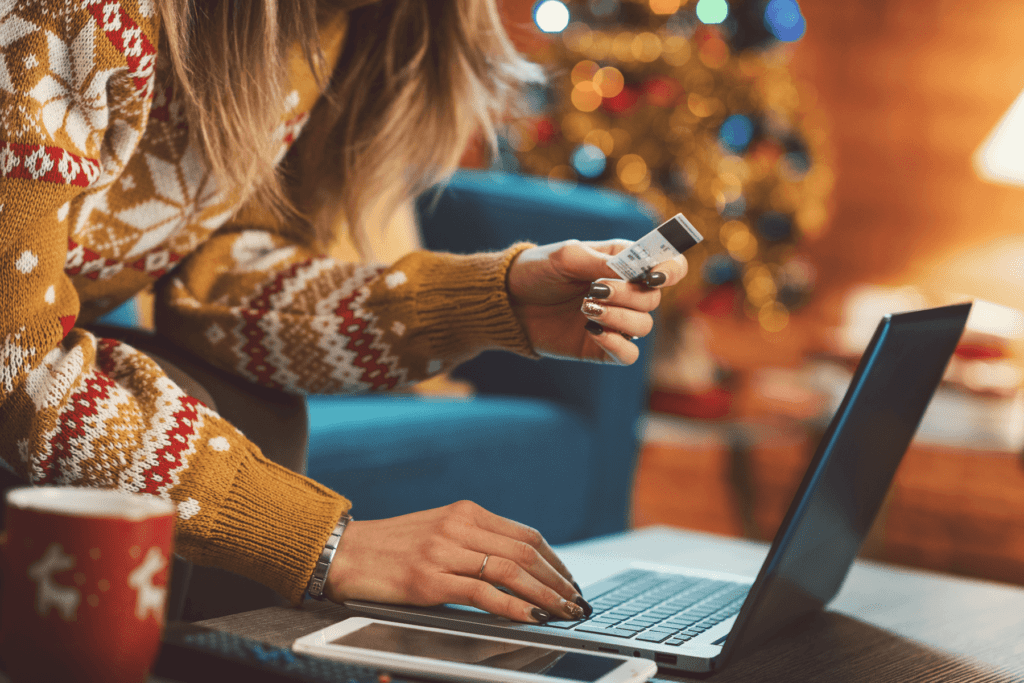 End of year online scams visualized. A woman is seen entering credit card information into a laptop