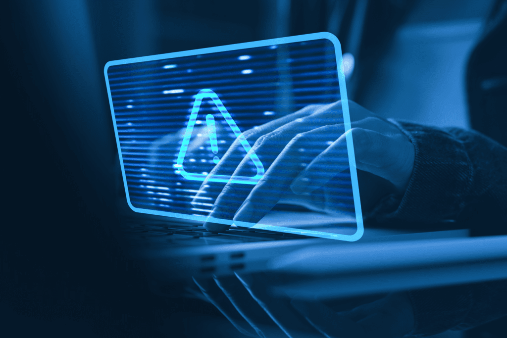 Decorative image for guide about how to identify malicious websites showing a person at a computer and a visual of a warning symbol implying a security error