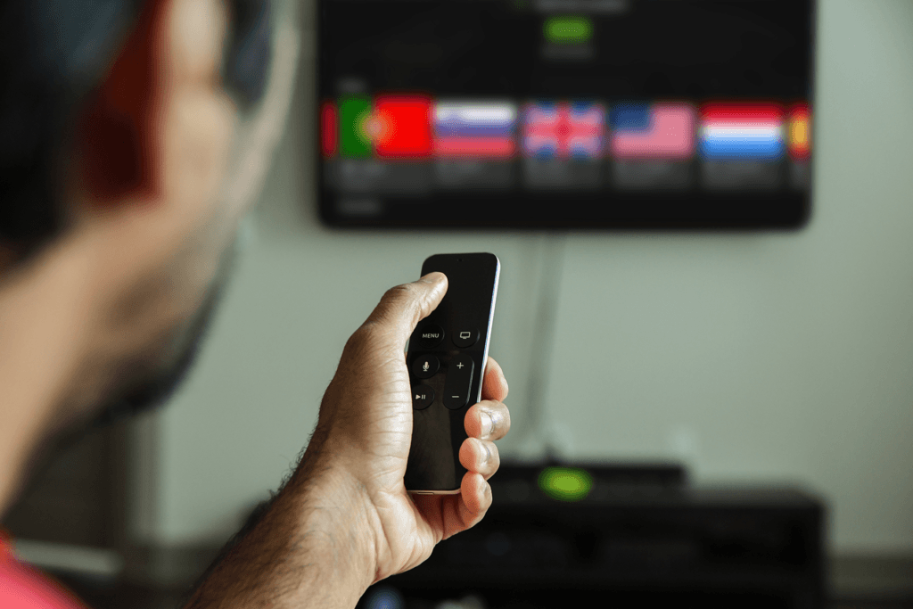 A man is seen using the IPVanish VPN app for Apple TV while holding a remote