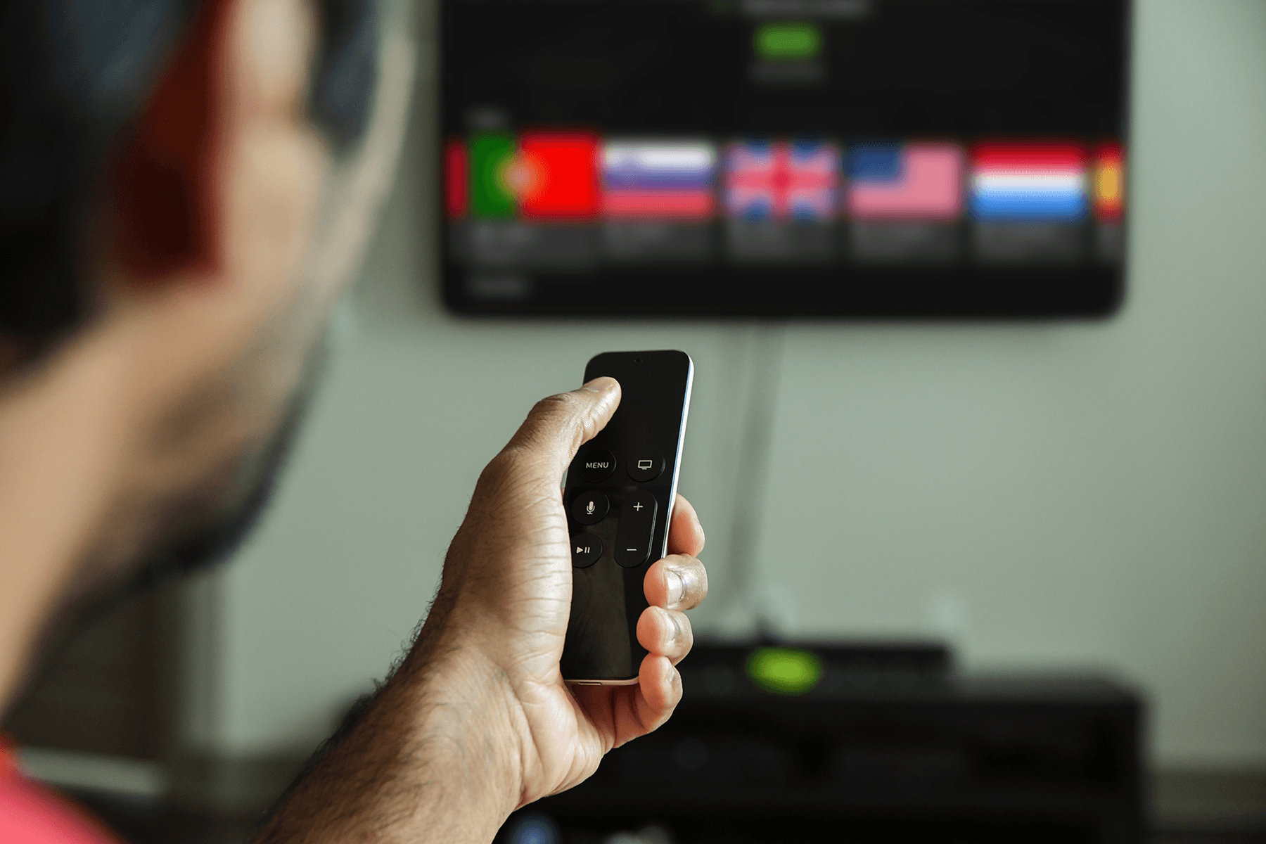 A man is seen using the IPVanish VPN app for Apple TV while holding a remote