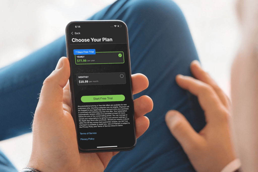 A man holds his mobile phone and the screen displaysthe IPVanish app at the 'Choose Your Plan' selection as he signs up for the VPN free trial